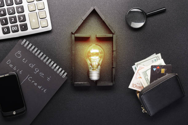 An illuminated house icon accompanied by financial elements including a budget sheet, debit and credit symbols, and money stacks, representing the concept of understanding borrowing power and financial decision-making for property investment.