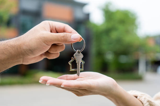 Two hands exchanging a key, symbolizing the journey to homeownership amidst fluctuating cash rates. This act represents the importance of financial readiness and long-term planning over waiting for the ideal cash rate.