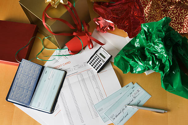 A table filled with holiday budgeting essentials, featuring a calculator, Christmas wrapping paper, a checkbook, and a credit card statement, symbolizing financial planning during the festive season.