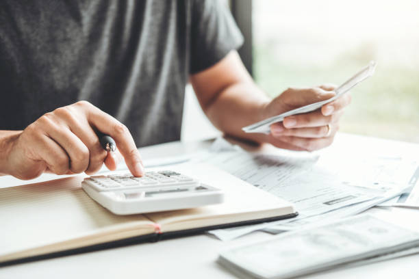 Person holding a document while using a calculator, reflecting financial decisions and planning ahead in light of the RBA's cash rate decision and potential rate cuts in 2025.